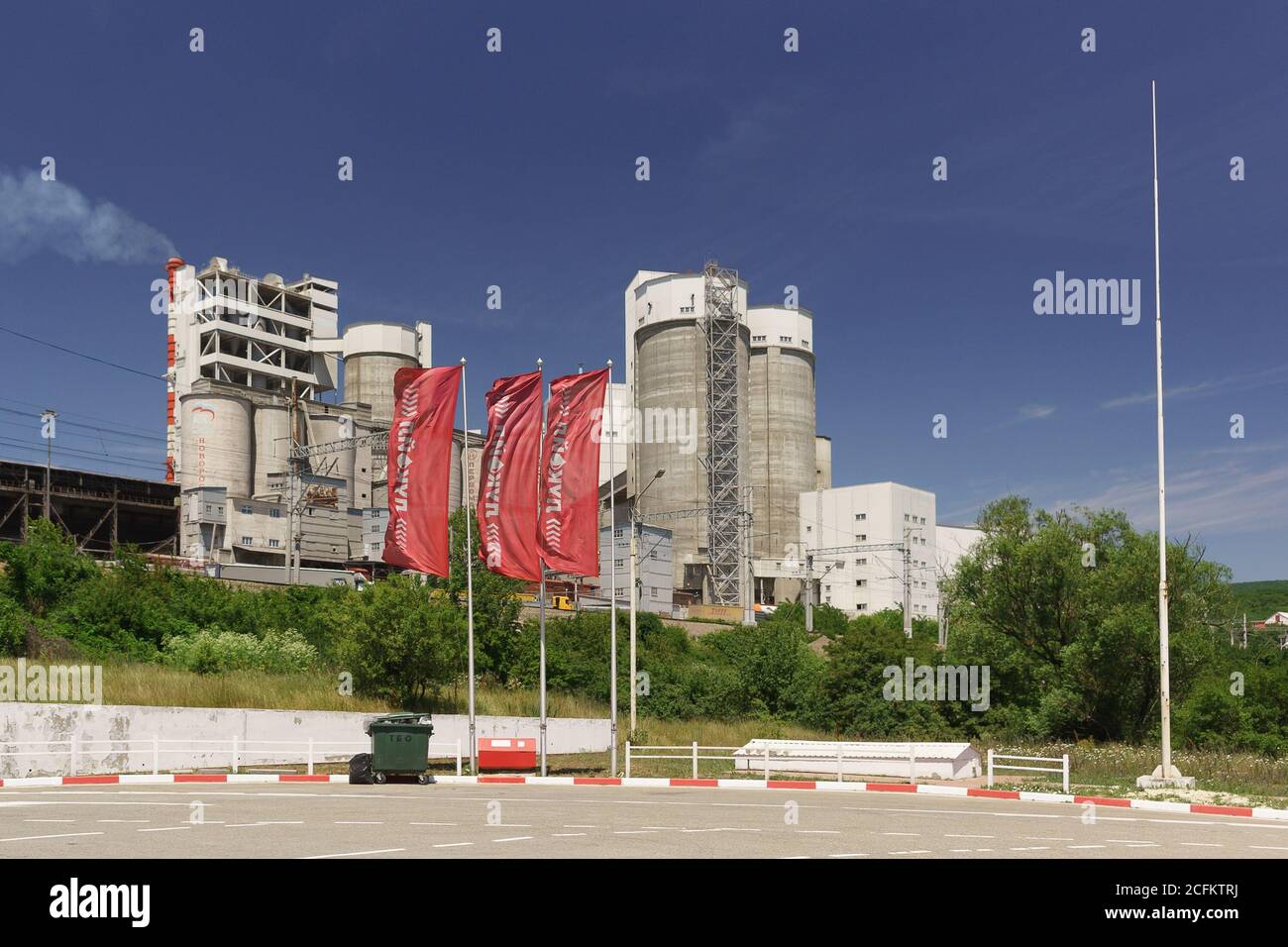 Russia, regione di Krasnodar, insediamento di Verkhnebakansky - 12 giugno 2018: Impianti di produzione di cemento Verkhnebakansky e bandiere rosse di LUKOIL ga Foto Stock