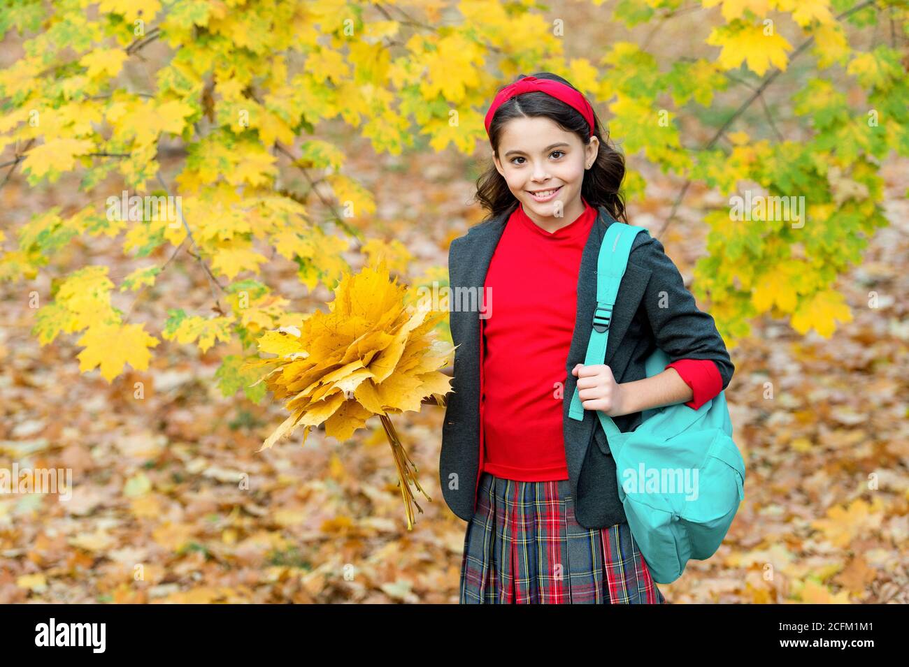 felice scuola ragazza manciata di foglie di acero giallo nel parco, tempo di scuola. Foto Stock
