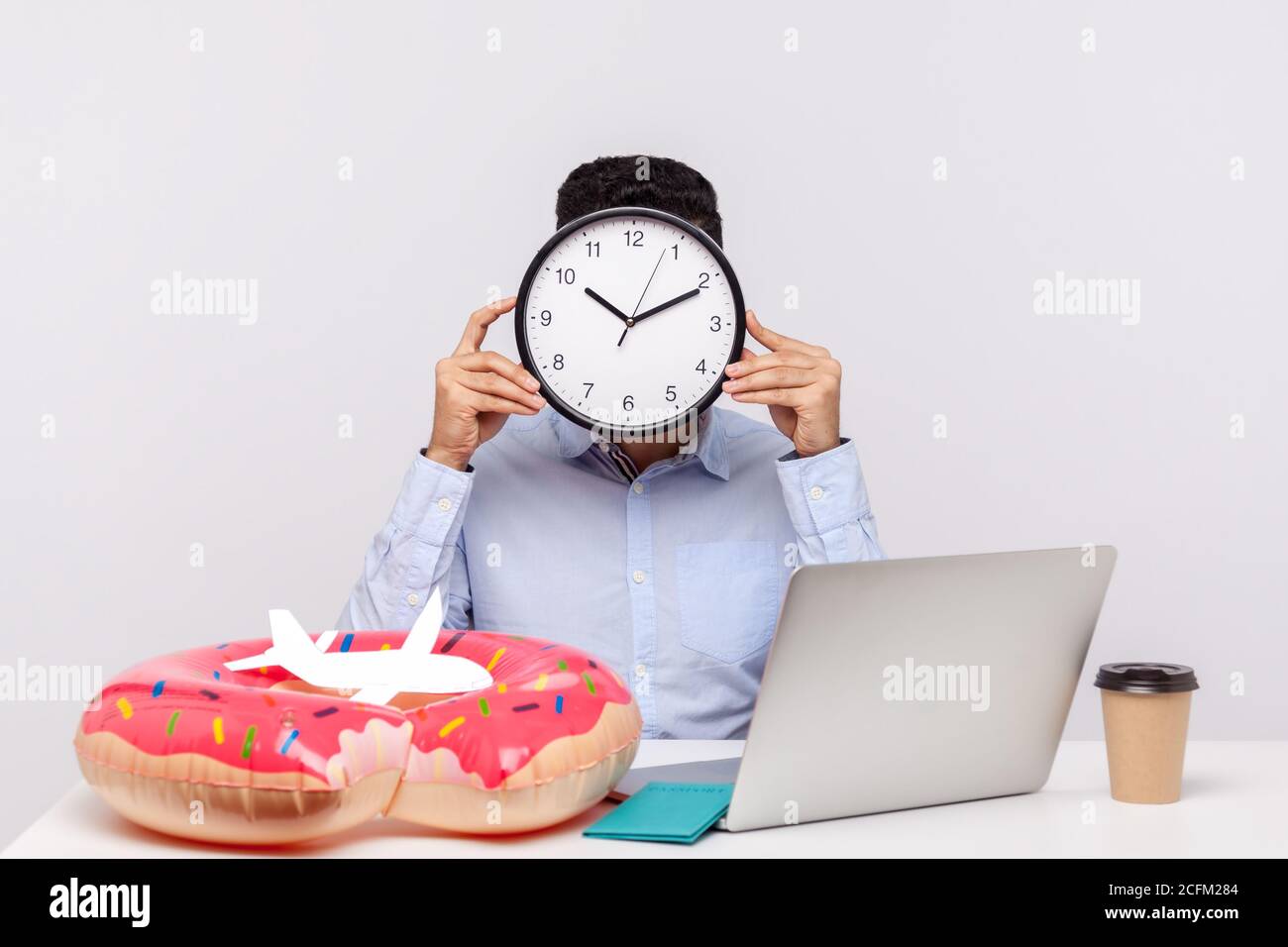 È il momento di riposarsi! Uomo sconosciuto che nasconde il volto dietro l'orologio, seduto in ufficio con passaporto con anello in gomma e aereo di carta sulla scrivania, dipendente chiede Foto Stock