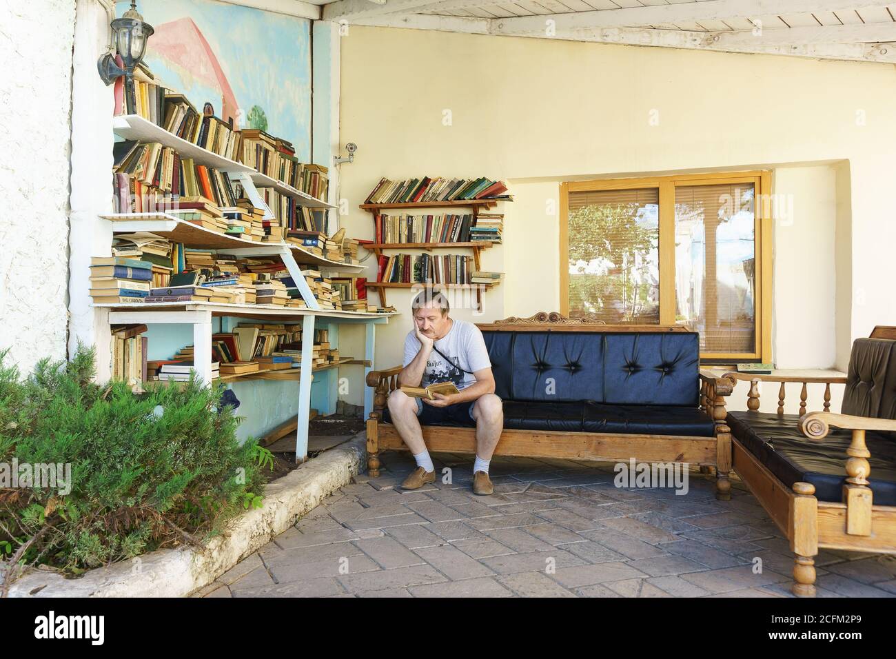Evpatoria, Crimea, Russia-8 settembre 2019: Un turista legge un libro in una piccola biblioteca sul territorio del caffè-Museo 'Yoskin kot' vicino alla yegiy Foto Stock
