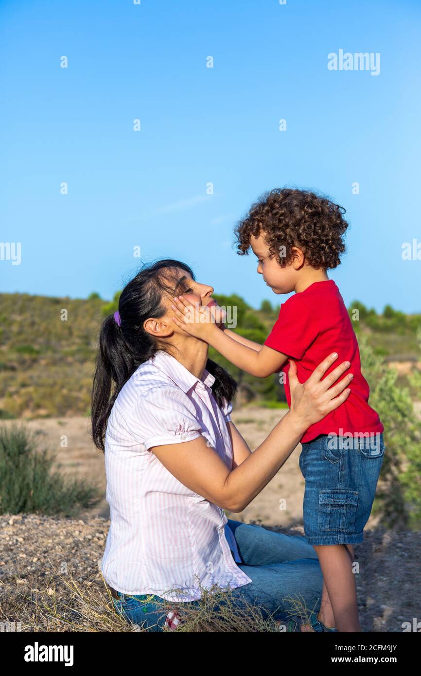 Bambino che esegue atto d'amore verso la madre con una carezza sul viso, felice e sorridente madre con il bel gesto del suo piccolo Foto Stock