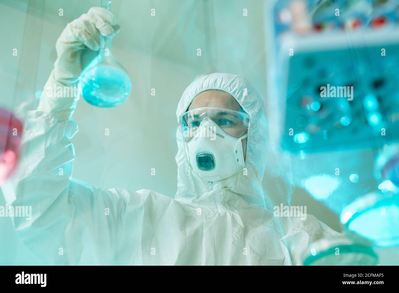 Giovane scienziata contemporanea che guarda il tubo con liquido blu sostanza Foto Stock