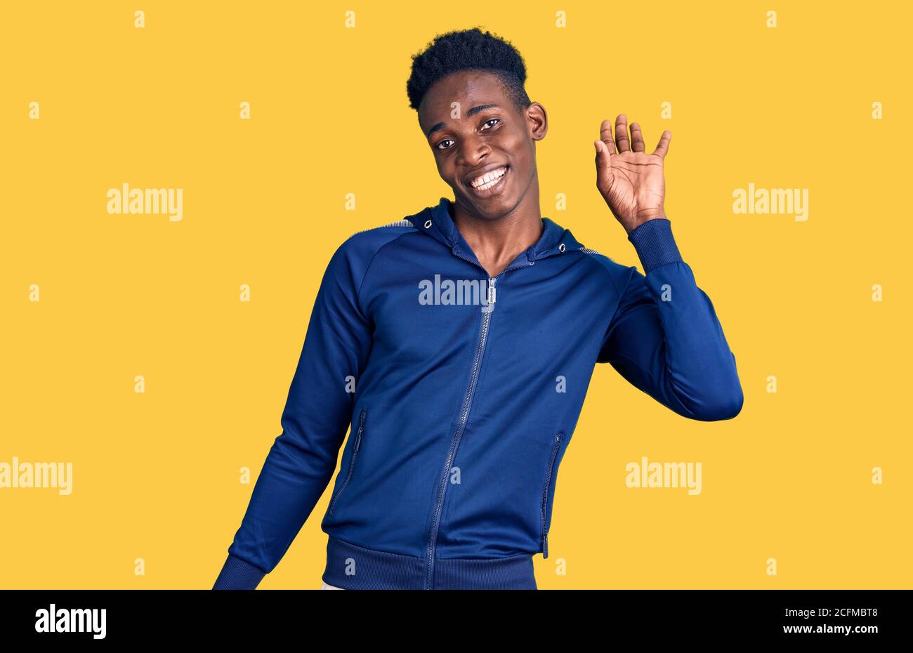 Giovane afroamericano che indossa una vita sportiva dicendo ciao felice e sorridente, amichevole gesto di benvenuto Foto Stock