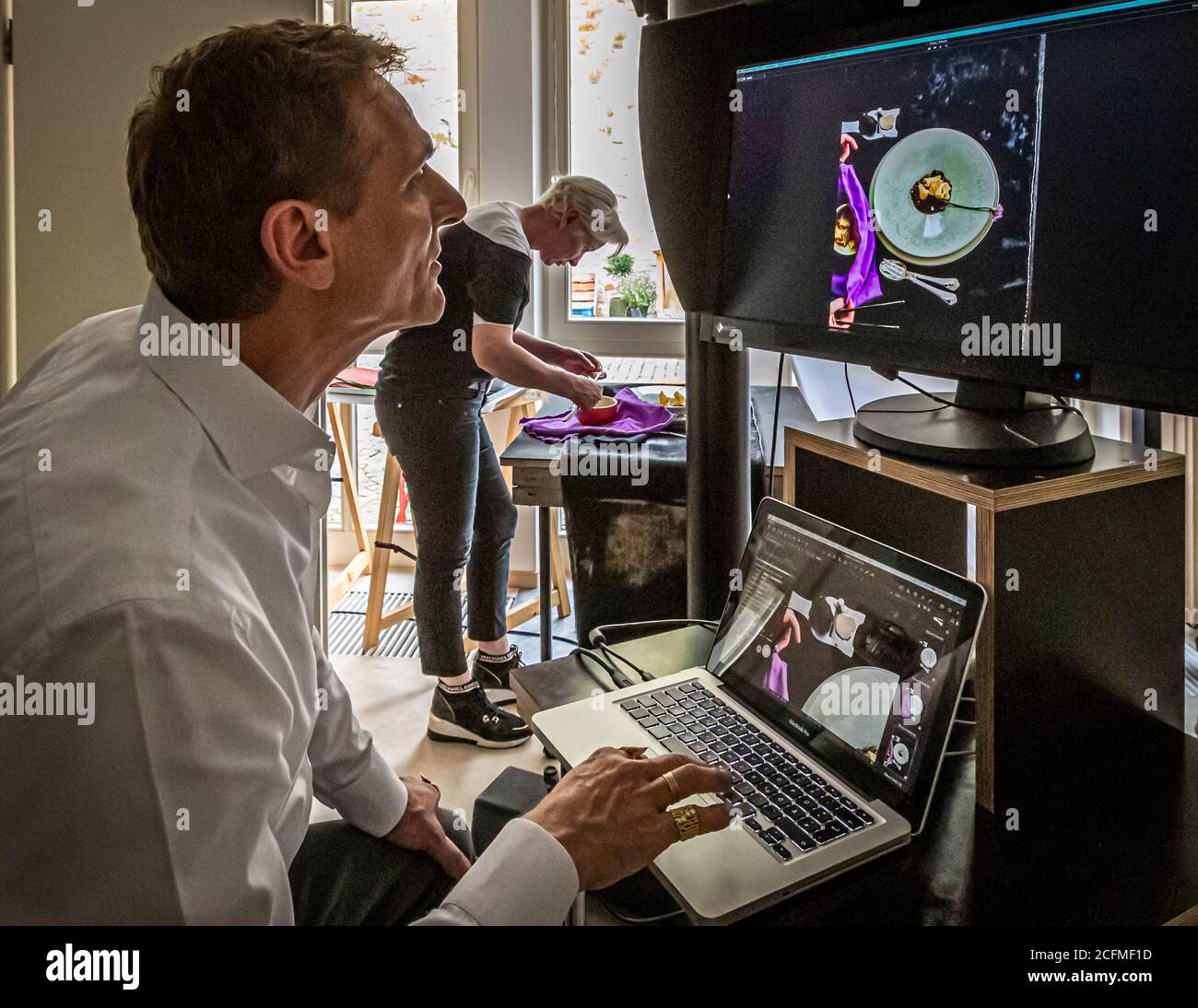 Uno sguardo critico al monitor. Produzione di un libro di cucina dalla cucina allo studio fotografico Foto Stock