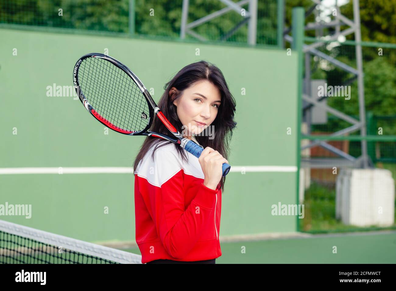 Ritratto di una bella giovane tennista femminile in abbigliamento sportivo con racchetta da tennis sul campo. Foto Stock