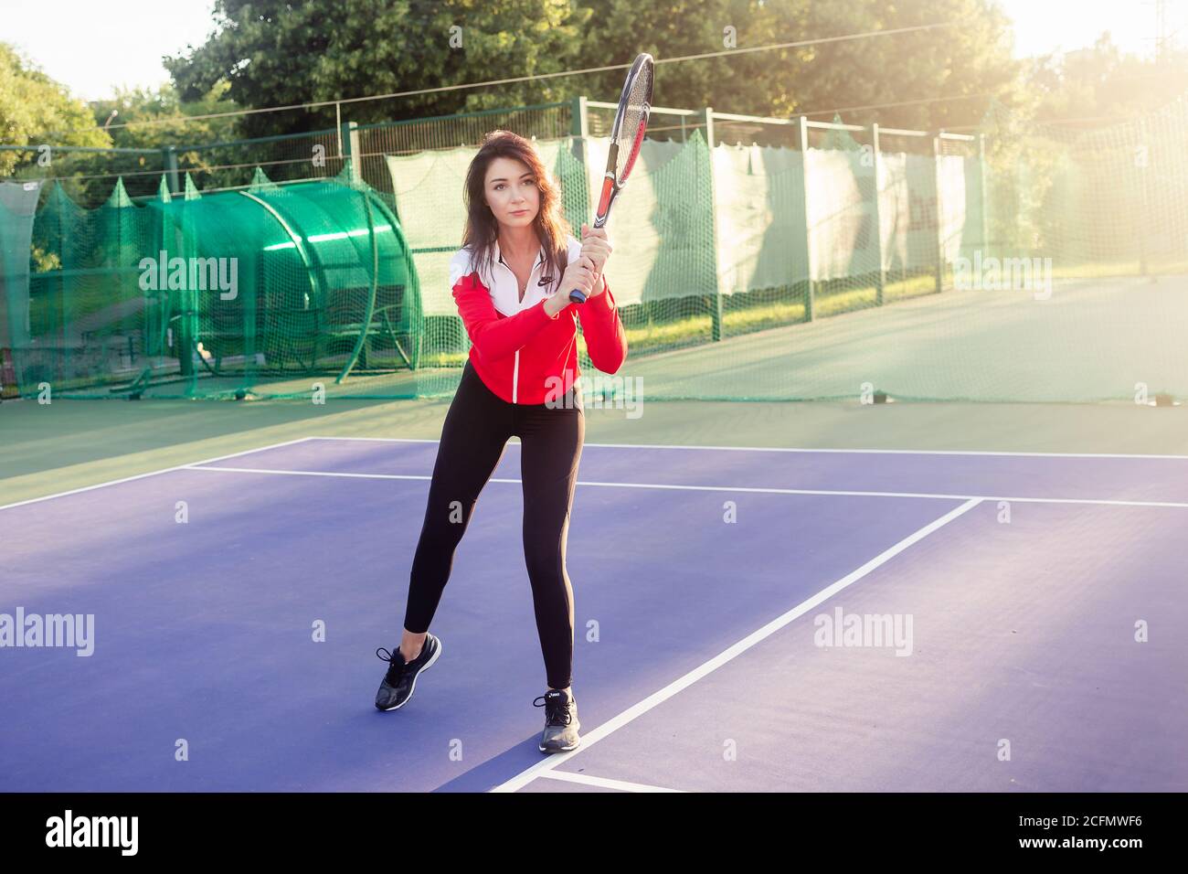 Ritratto di una bella giovane tennista femminile in abbigliamento sportivo con racchetta da tennis sul campo. Foto Stock