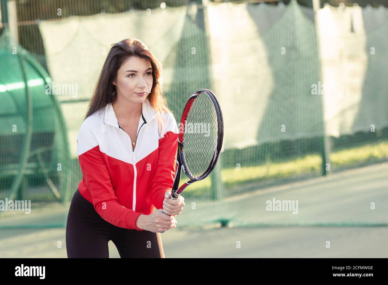 Ritratto di una bella giovane tennista femminile in abbigliamento sportivo con racchetta da tennis sul campo. Foto Stock