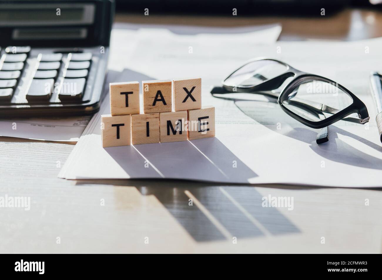 Tempo fiscale lettere in legno con forma fiscale, bicchieri e calcolatrice Foto Stock