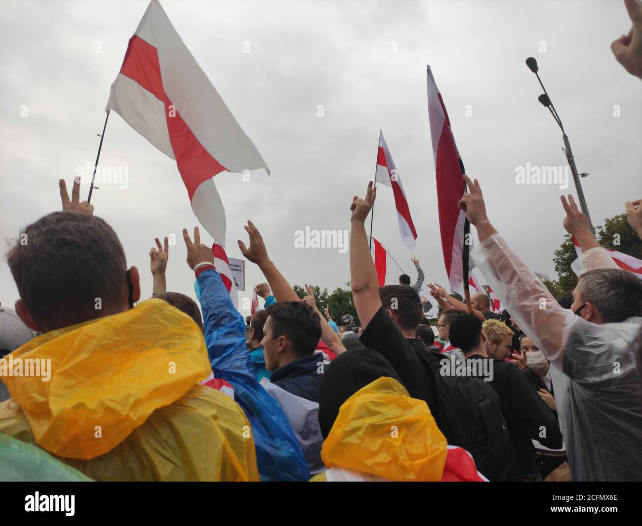 Minsk / Bielorussia - 6 settembre 2020: Manifestanti in colorati impermeabile alzando le mani con il segno della vittoria e le bandiere in aria Foto Stock