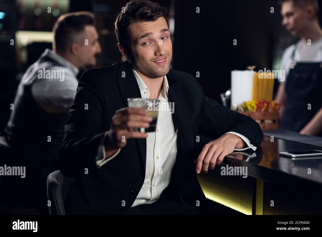 un bell'uomo posa per una foto al bar di un ristorante con un cocktail in  mano, ritratto Foto stock - Alamy