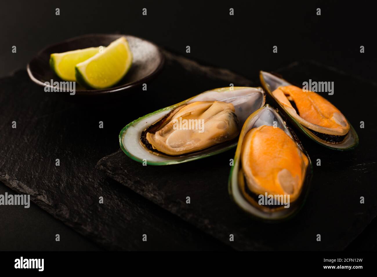 Cozze a conchiglia verde della Nuova Zelanda su fondo piatto in pietra nera e. lime elegante studio di lusso Foto Stock