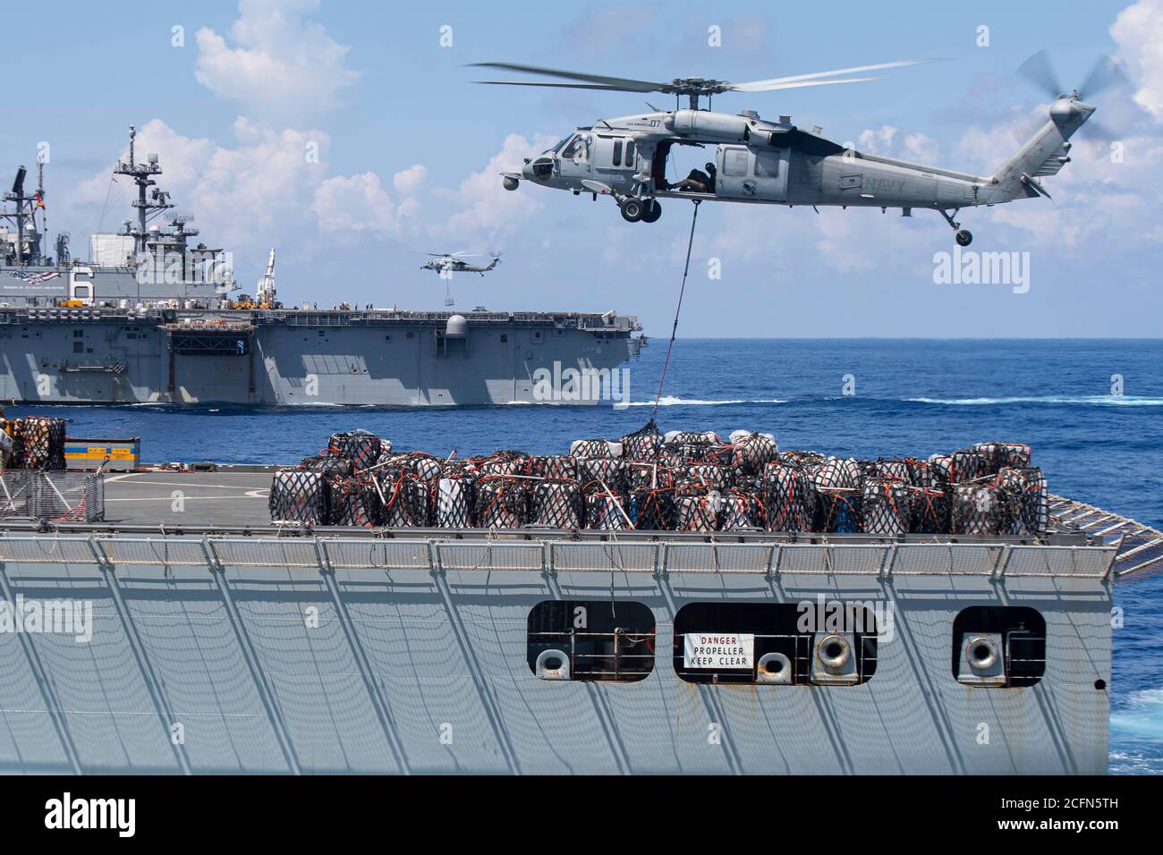 MARE DELLE FILIPPINE (settembre 03, 2020) - gli elicotteri Sea Hawk MH-60S degli Arcangeli di Helicopter Sea Combat Squadron (HSC) 25 trasportano pallet di merci secche dalla nave da carico/munizioni USNS Charles Drew (T-AKE 10) alla nave d'assalto anfibia USS America (LHA 6) durante un rifornimento in corso. L'America, parte del gruppo americano Amphibious Ready assegnato a Amphibious Squadron 11, insieme alla 31ma unità di spedizione marina, opera nell'area di responsabilità della settima flotta statunitense per migliorare l'interoperabilità con alleati e partner e servire come forza di risposta pronta a difendere i piselli Foto Stock