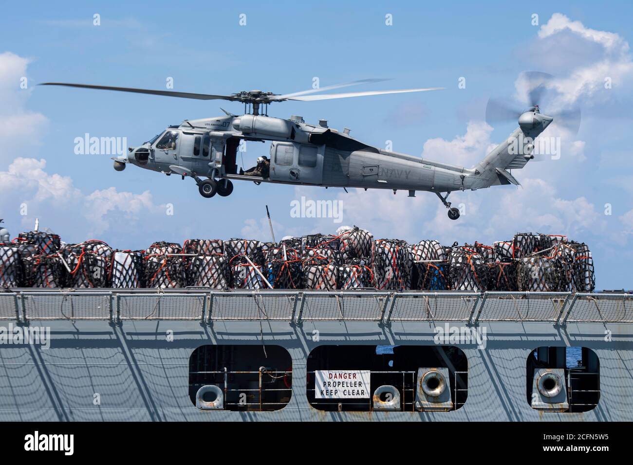 MARE DELLE FILIPPINE (settembre 03, 2020) - un elicottero MH-60S Sea Hawk degli Arcangeli di Helicopter Sea Combat Squadron (HSC) 25 consegna pallet di merci secche dalla nave da carico/munizioni USNS Charles Drew (T-AKE 10) alla nave d'assalto anfibia USS America (LHA 6) durante un rifornimento in corso. America, parte del Gruppo Amphibious Ready America assegnato a Amphibious Squadron 11, insieme alla 31esima unità di spedizione marina, opera nell'area di responsabilità della 7esima flotta statunitense per migliorare l'interoperabilità con alleati e partner e servire come forza di risposta pronta a difendere p Foto Stock