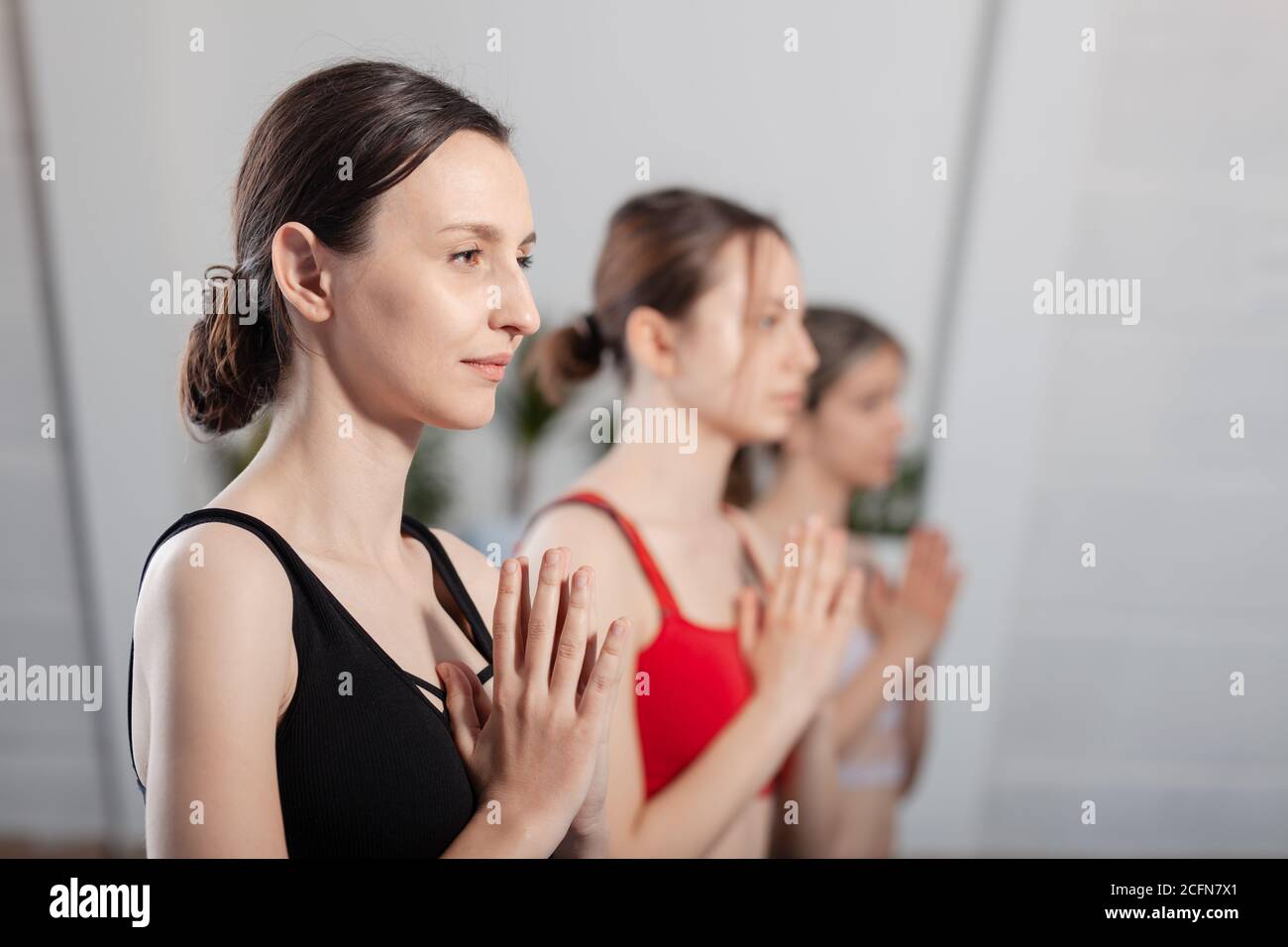 Tre ragazze che praticano lo yoga. Istruttore di yoga con i suoi studenti che meditano in uno studio. Foto Stock