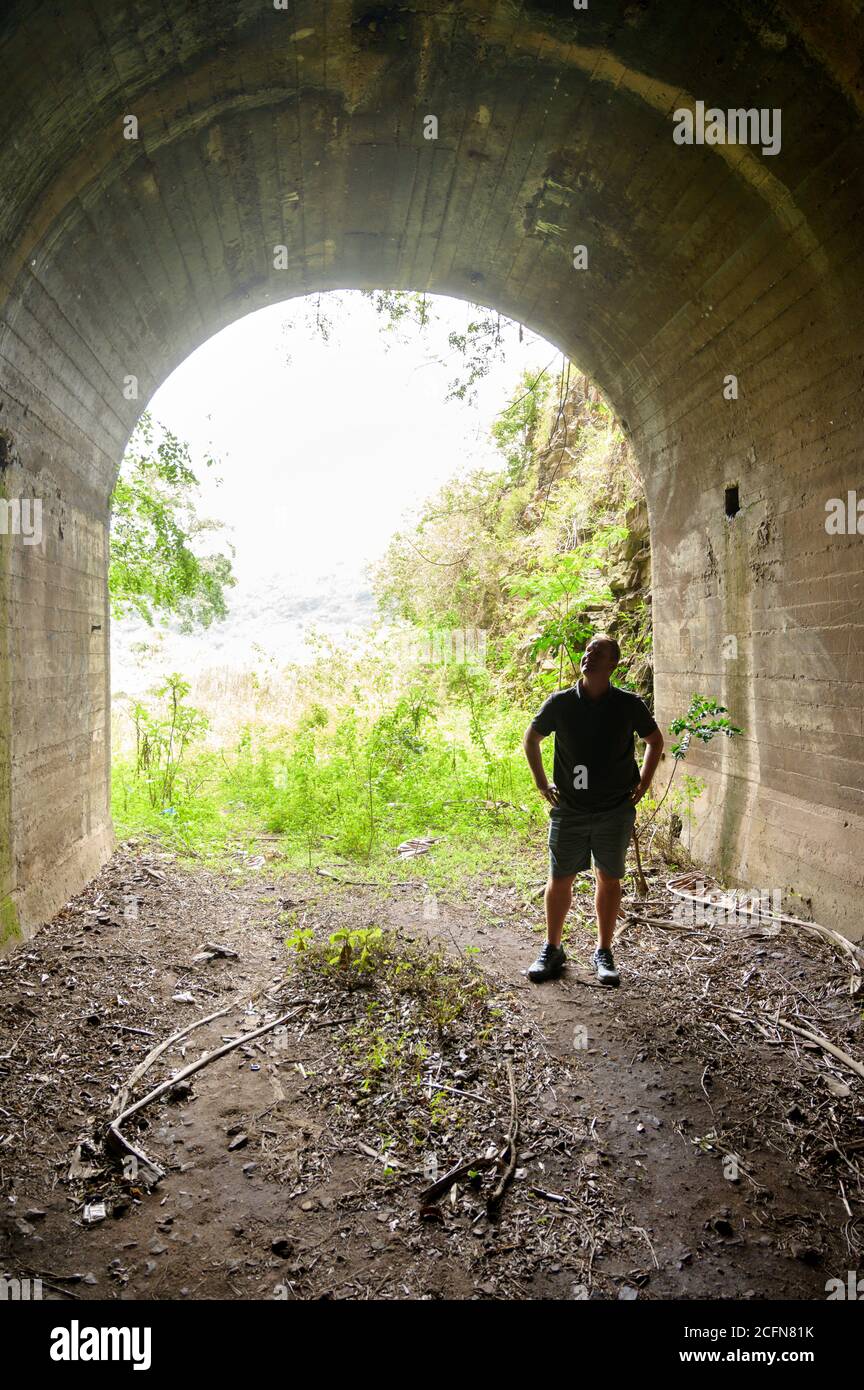 Un uomo in un tunnel ferroviario abbandonato in una fitta foresta e giungla. Kwa Zulu-Natal, Sudafrica. Foto Stock