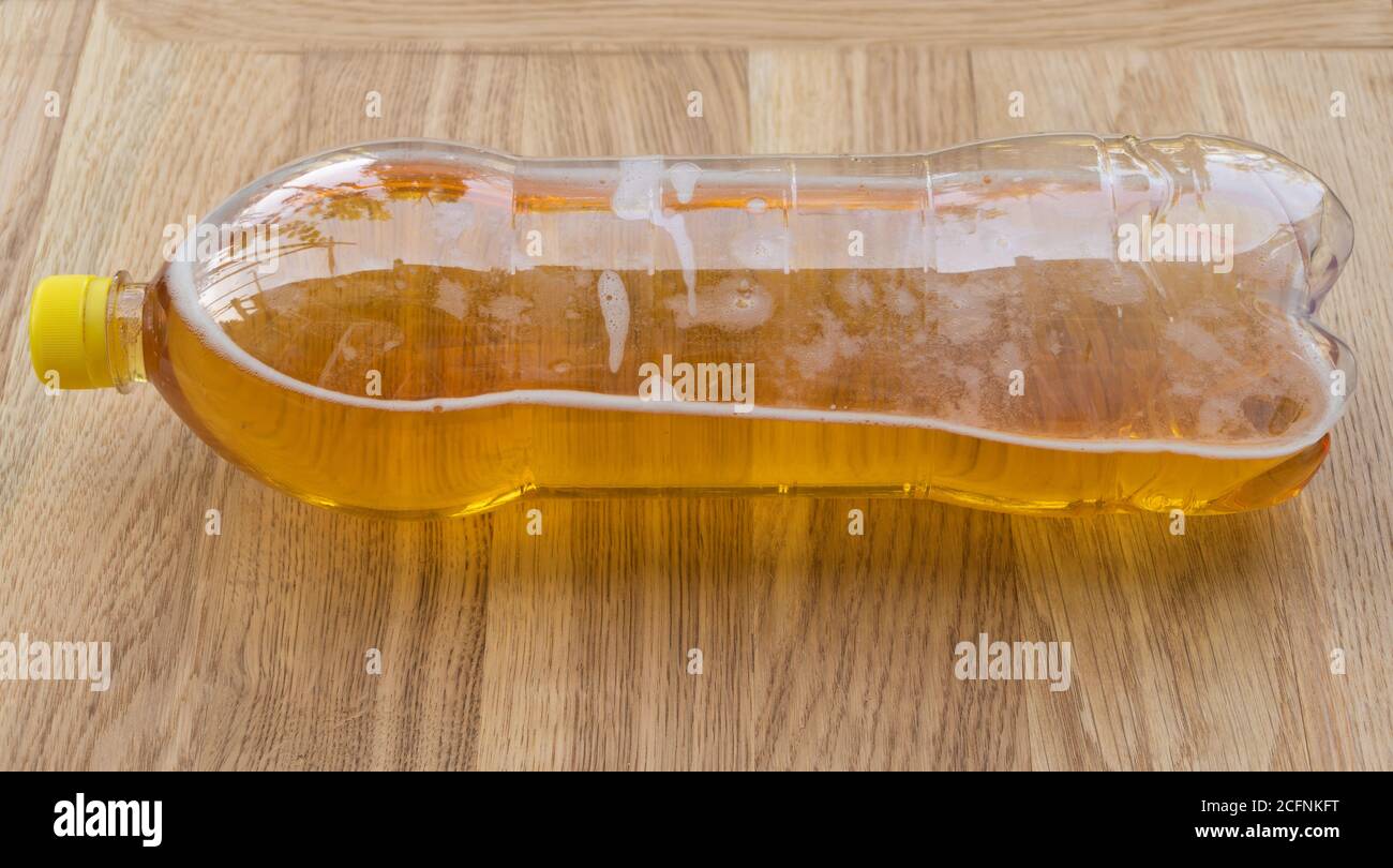 Birra in una bottiglia di plastica su sfondo di legno Foto Stock