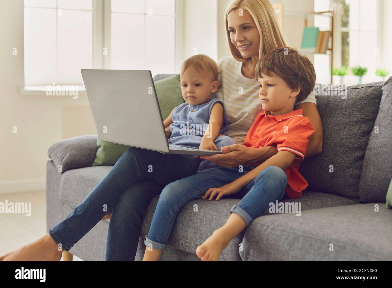 Mamma e bambini che usano il computer portatile per guardare i cartoni animati educativi o per videochattare con i parenti Foto Stock
