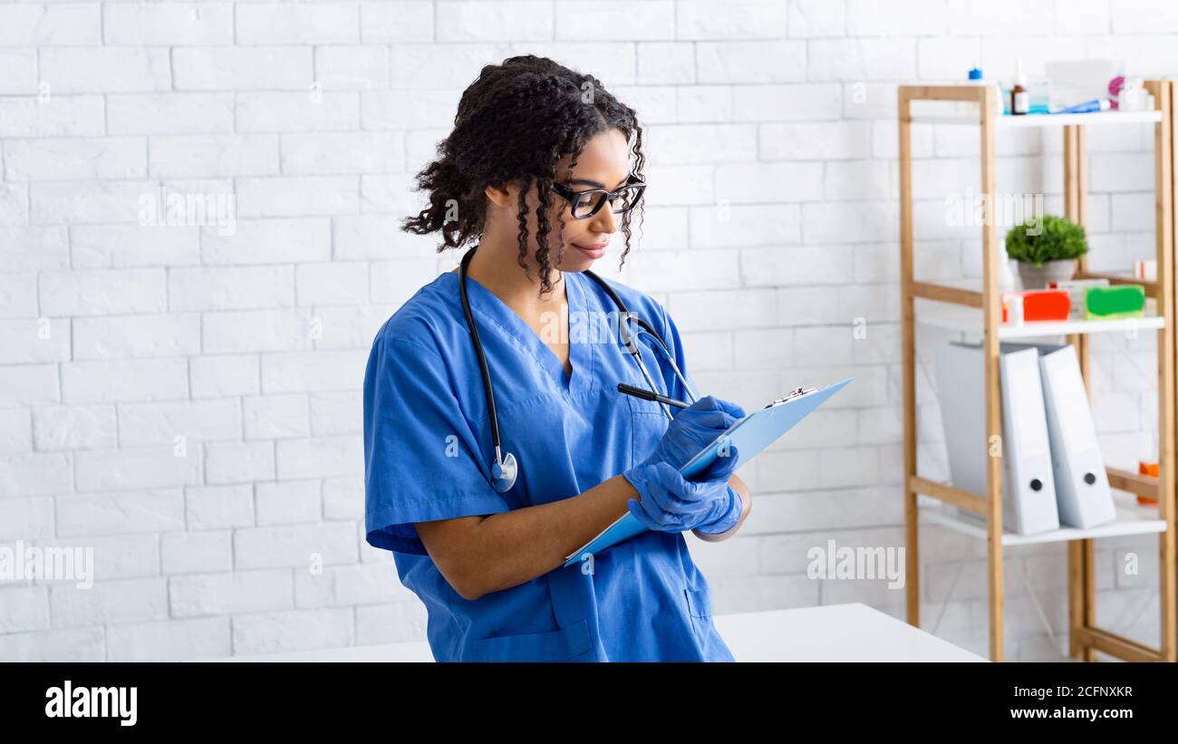 Ritratto del medico veterinario afroamericano che scrive sulla clipboard a. clinica animale Foto Stock