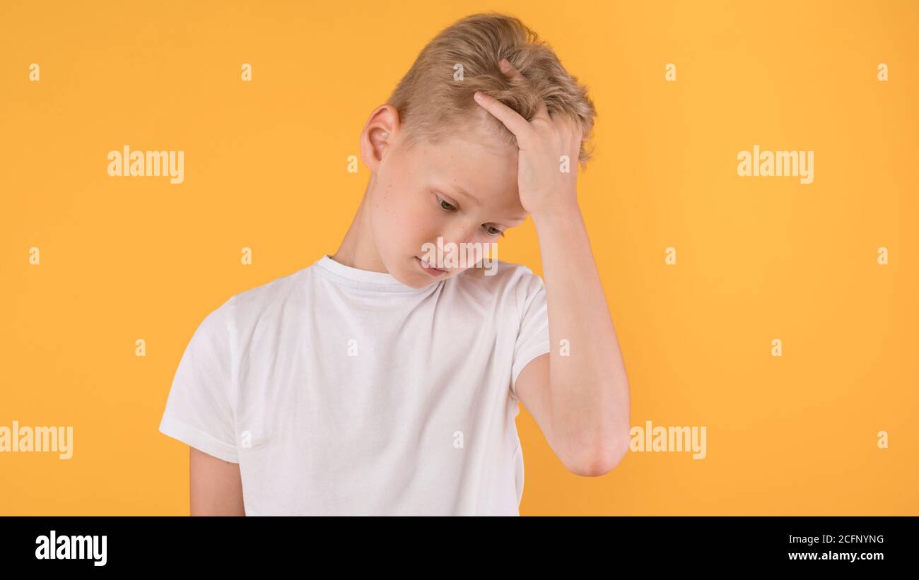 Ritratto di ragazzo infelice che afferra la testa, guardando verso il basso Foto Stock
