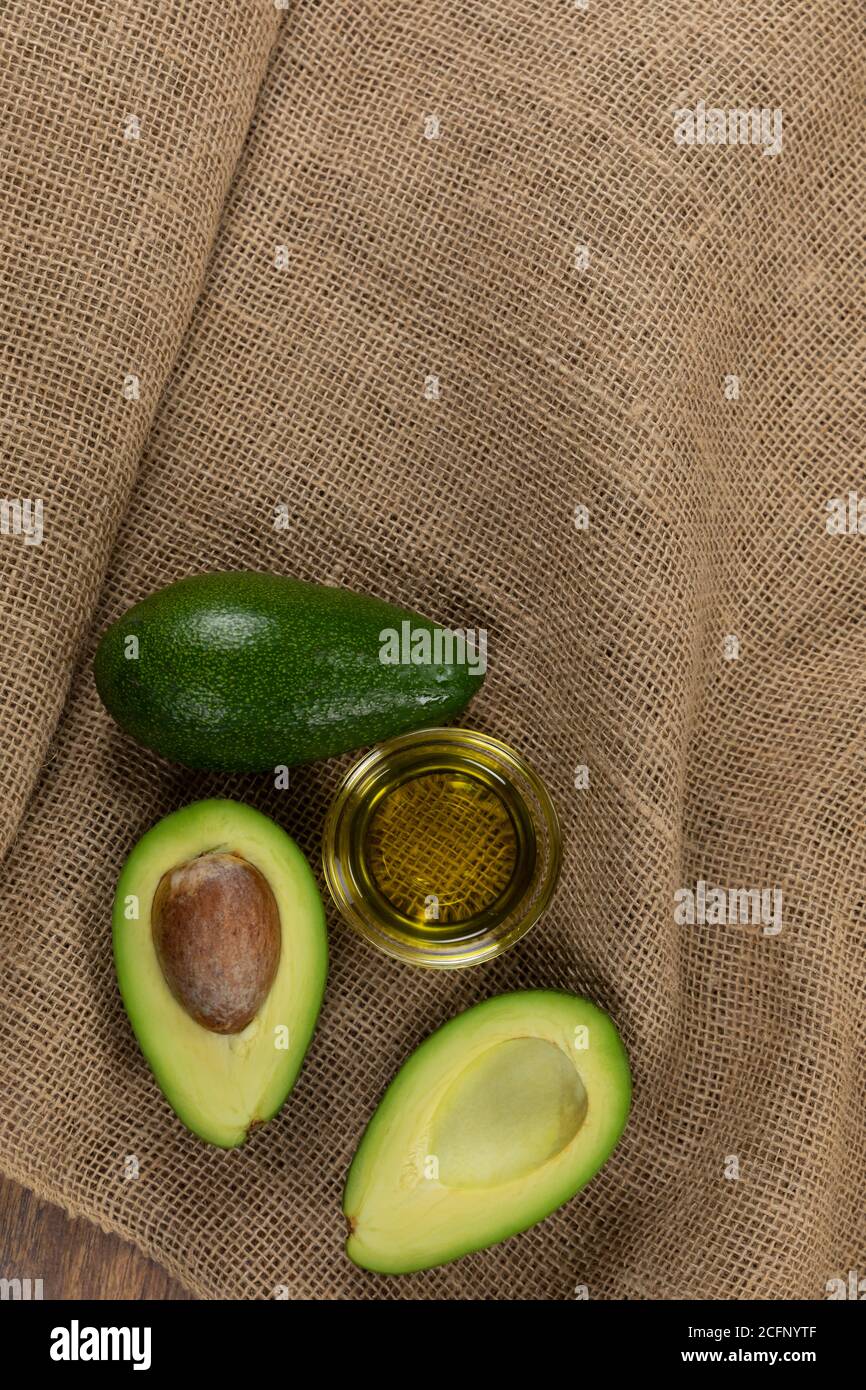 Vista di due avocado e bottiglia di olio d'oliva su panno sfondo Foto Stock