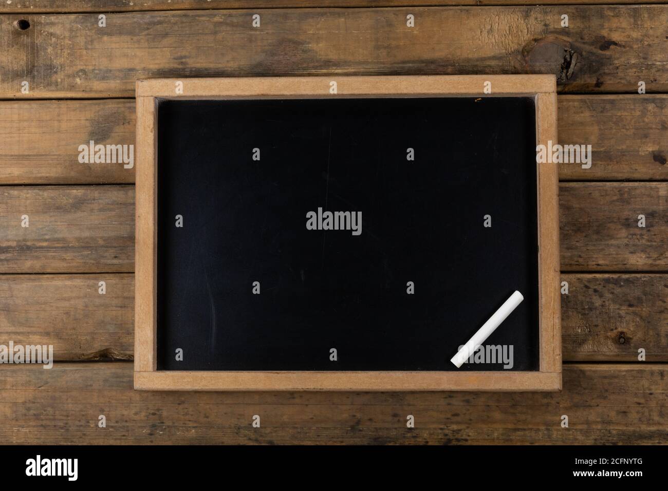 Vista di una lavagna nera con un gesso su legno sfondo della tabella Foto Stock
