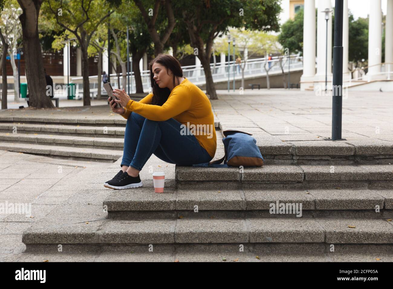 Donna caucasica curvilinea che usa il suo smartphone per le strade della città Foto Stock