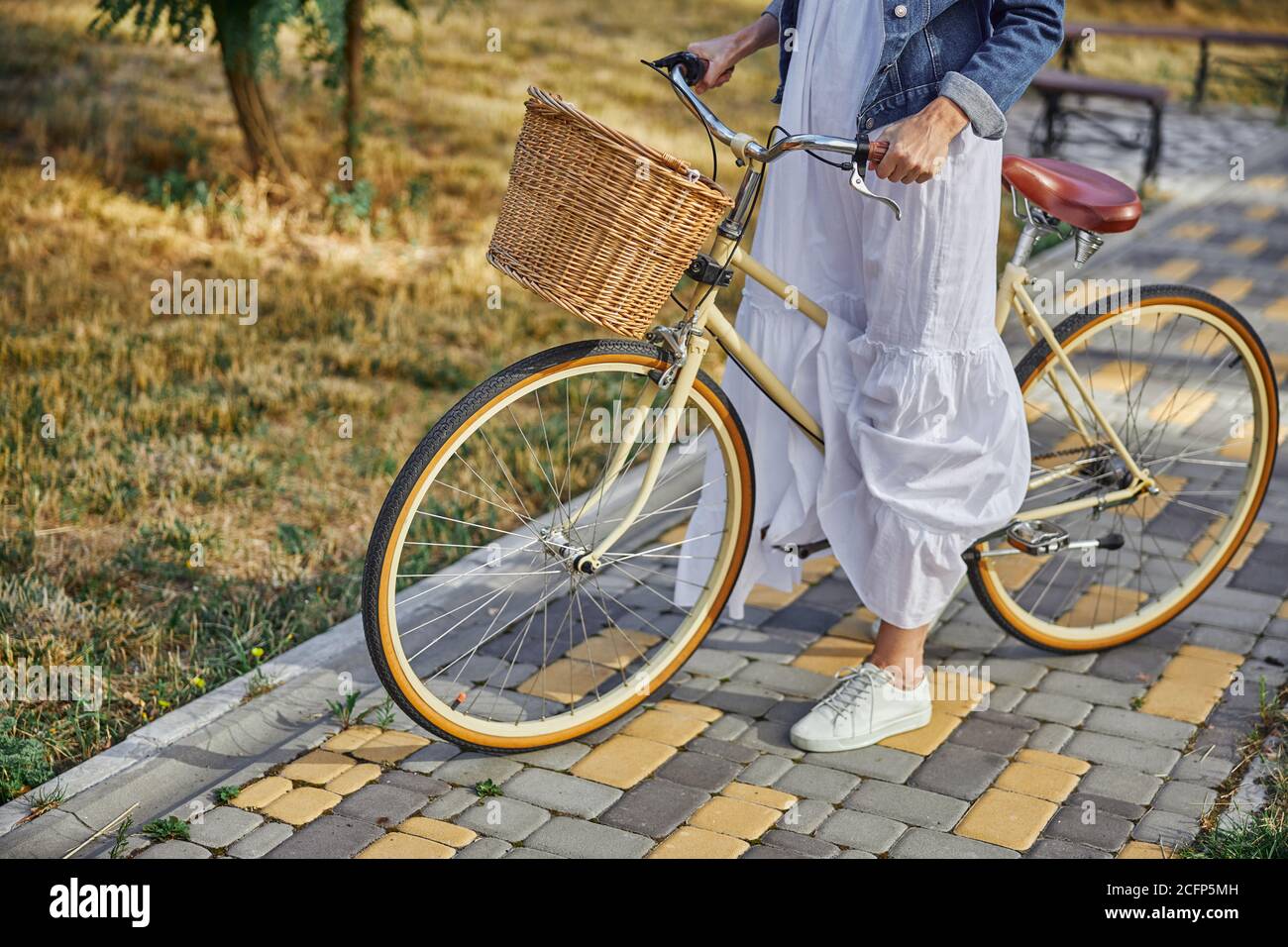 Donna elegante che regge il manubrio di una bicicletta da città con cesto  Foto stock - Alamy