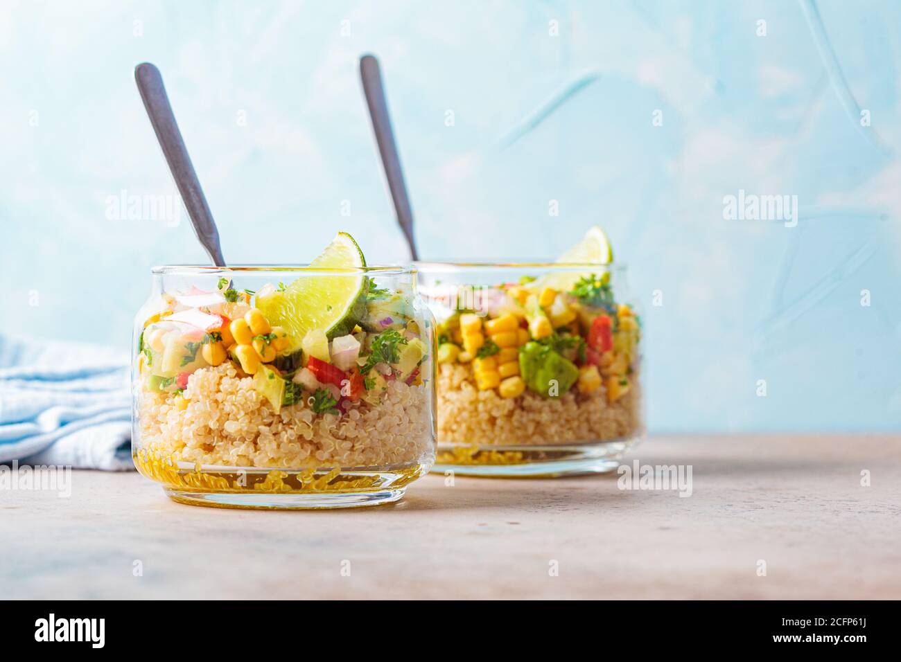 Insalata vegana con verdure e quinoa in vasetti di vetro, sfondo blu. Takeaway, cibo vegetariano sano, concetto zero rifiuti. Foto Stock