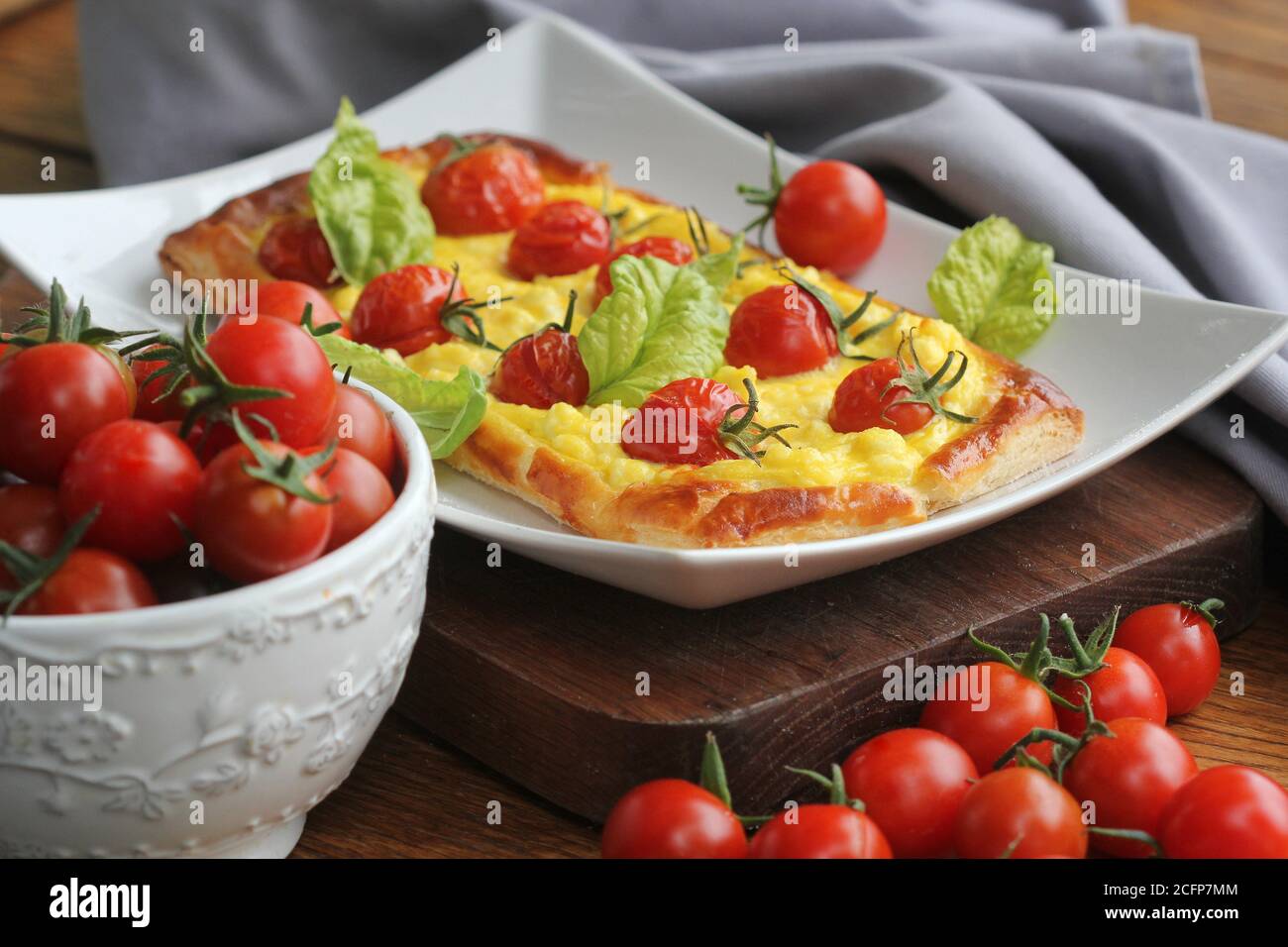 Crostata di pomodoro fresco, pasta sfoglia ricoperta di ricotta, formaggio e pomodori ciliegini Foto Stock