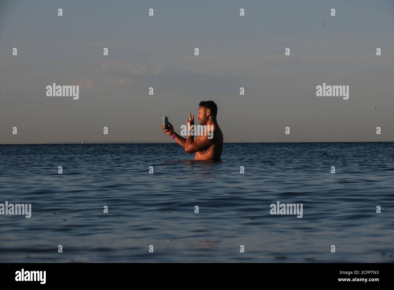 Melbourne Australia; parlare al telefono mentre si è in vita in acqua. Un uomo usa il suo telefono mentre si trova nella baia di Port Phillip. Foto Stock