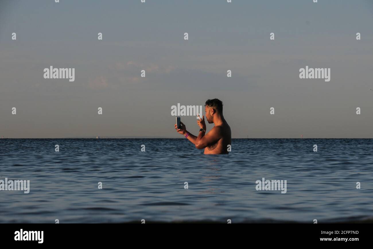 Melbourne Australia; parlare al telefono mentre si è in vita in acqua. Un uomo usa il suo telefono mentre si trova nella baia di Port Phillip. Foto Stock