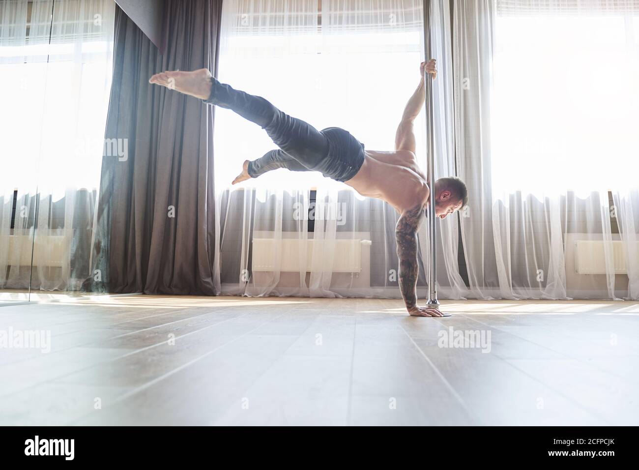 Forte giovane uomo ballerino allenamento sul palo Foto Stock