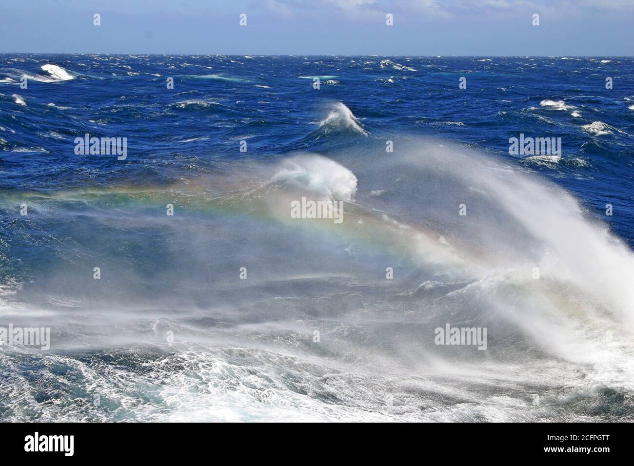 Mari accidentati dell'oceano pacifico meridionale, enormi onde con arcobaleno che si mostra nella schiuma proveniente dalla cima delle onde in crash, la Nuova Zelanda Foto Stock