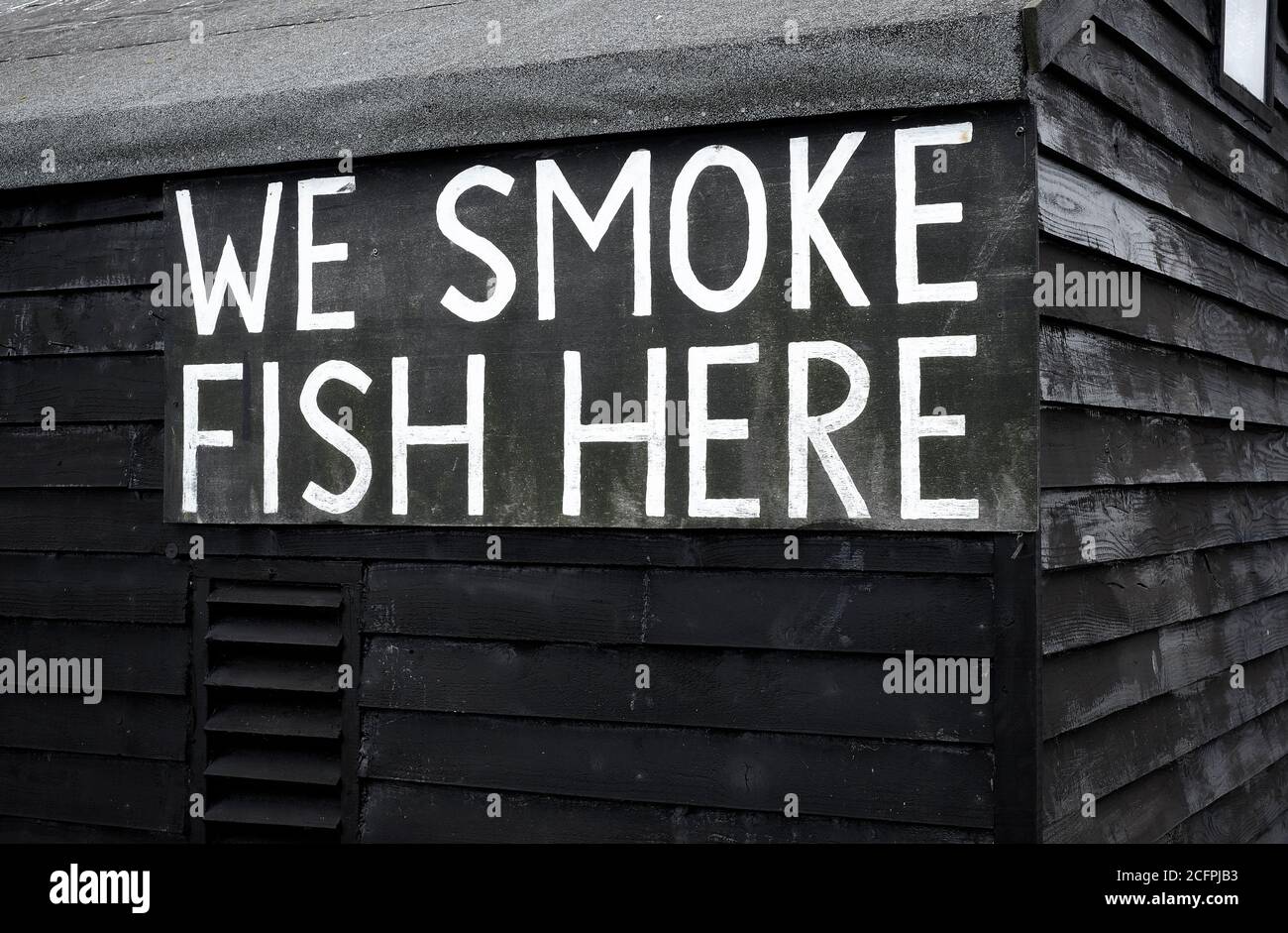 fumiamo pesce qui segno su capanna di legno verniciato nero, aldeburgh, suffolk, inghilterra Foto Stock