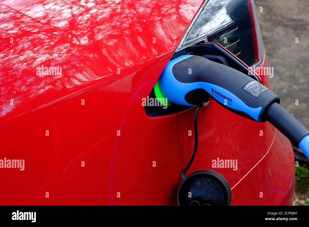 auto elettrica rossa in carica tramite cavo di alimentazione Foto Stock