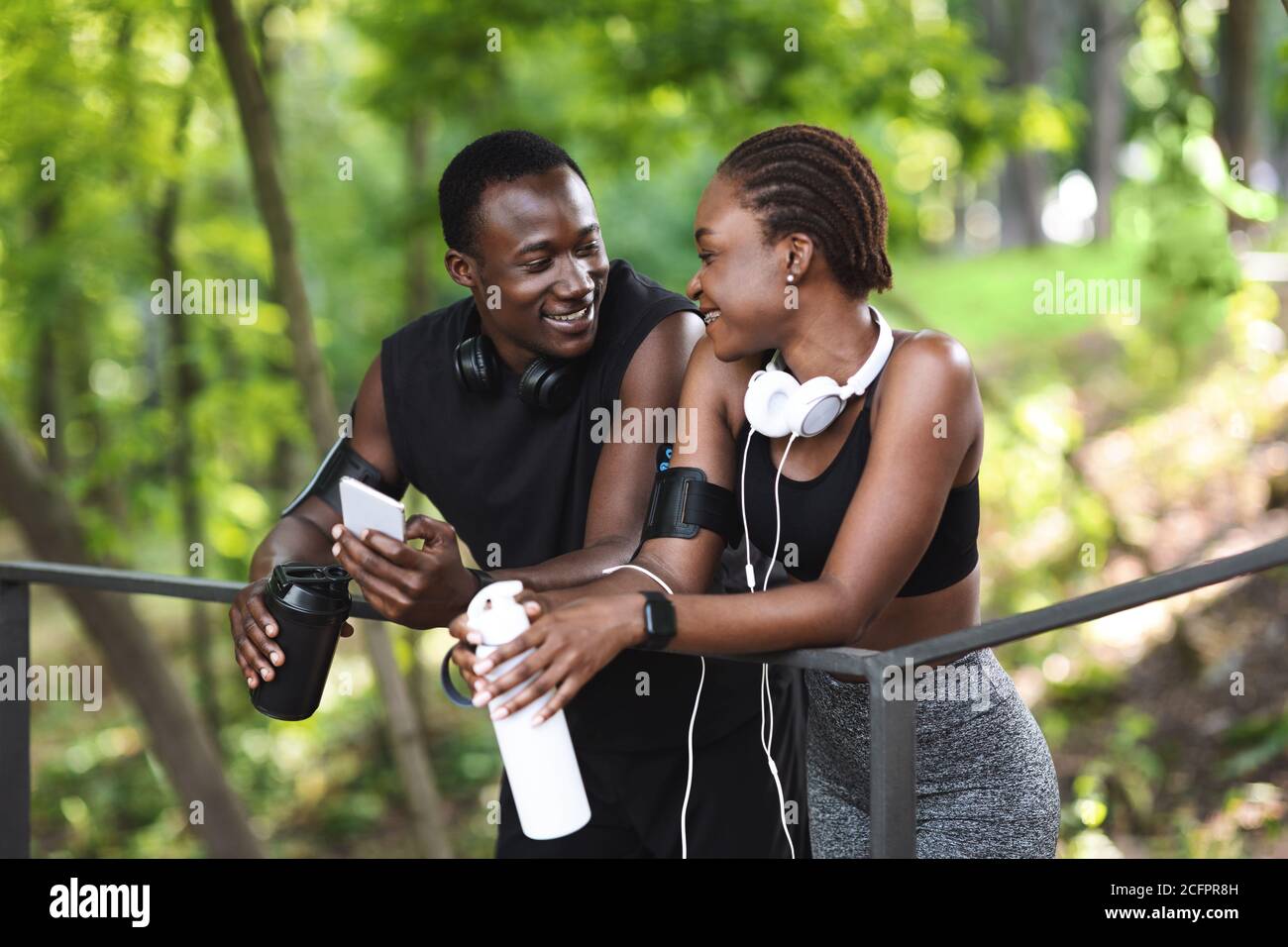 Lo sport si unisce. Romantica coppia nera sportiva rilassante all'aperto dopo un allenamento in fitness insieme Foto Stock
