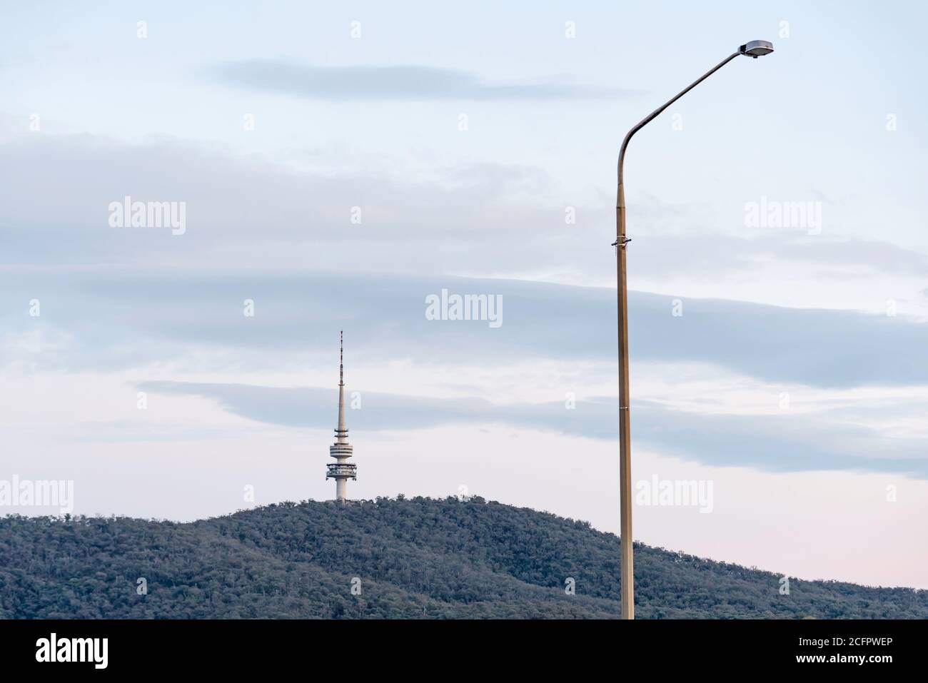 Due linee verticali formate da una torre Telstra distante sulla montagna Nera e chiudere una luce elettrica stradale a Canberra, Australia Foto Stock