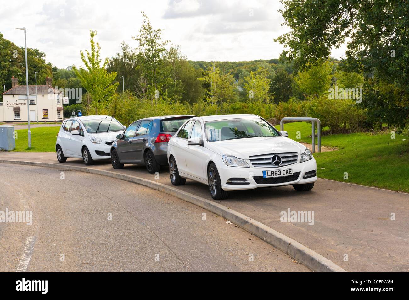 Tre auto parcheggiate su un marciapiede che blocca parzialmente il percorso per i pedoni. Foto Stock