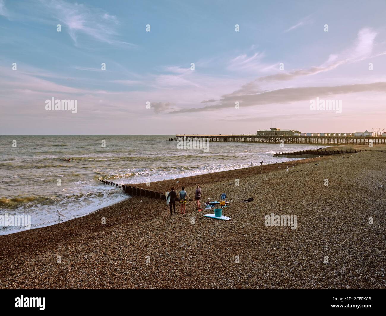 I visitatori della spiaggia di Hastings godono della vista del molo di Hastings durante l'alta marea in estate, Hastings, East Sussex, Inghilterra UK - estate 2020 Foto Stock