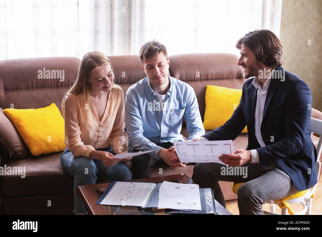Realtor sicuro che mostra il programma della casa a coppia dei compratori potenziali all'interno Foto Stock