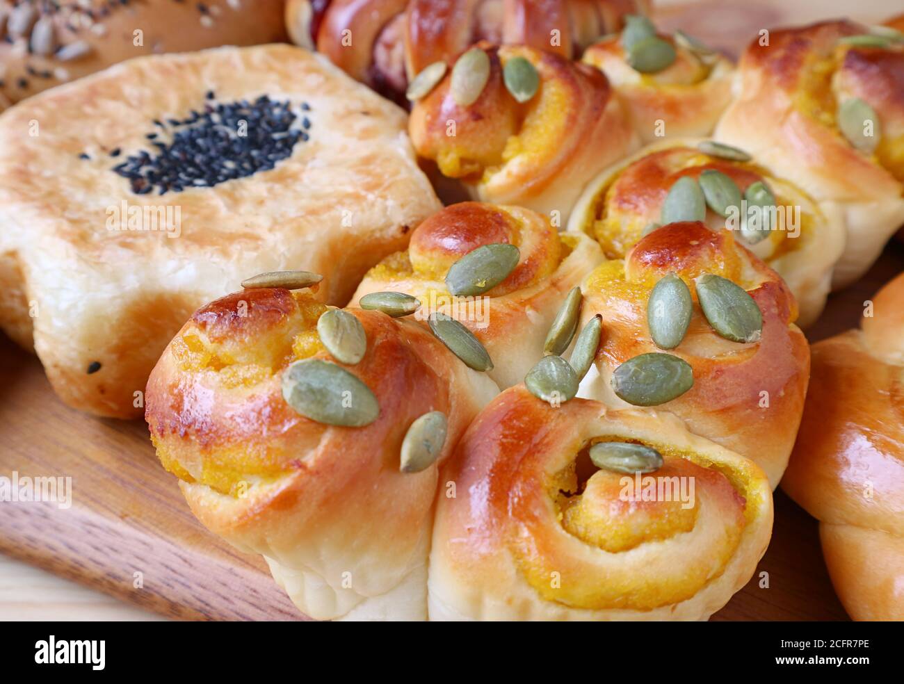 Rollino di zucca di closeup con semi assortiti e cereali pane sano in background Foto Stock