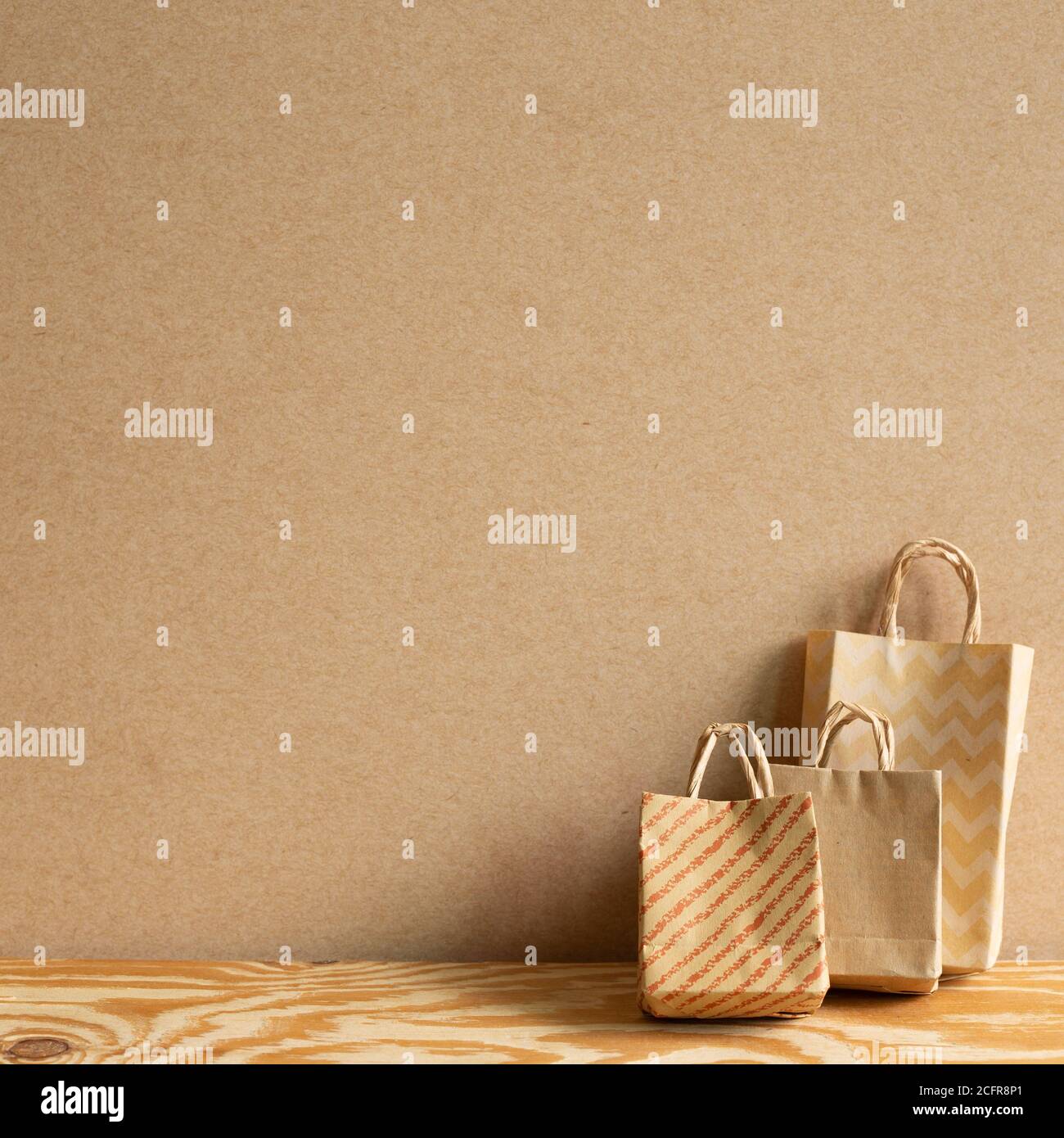Borse di carta Kraft su tavolo di legno con sfondo marrone Foto Stock