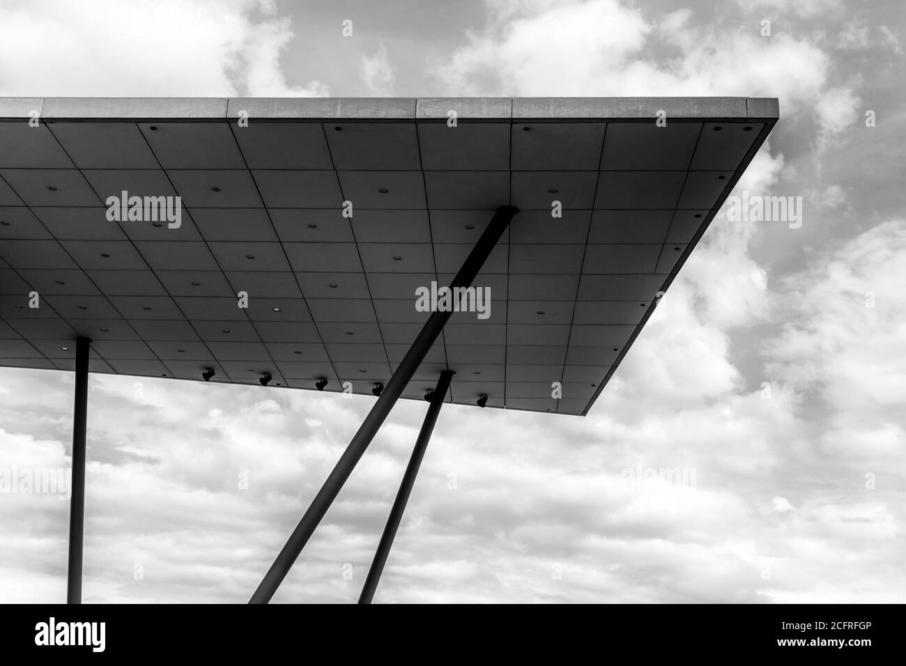 Un moderno tetto architettonico in cemento su tralicci in acciaio con nuvoloso cielo dietro Foto Stock