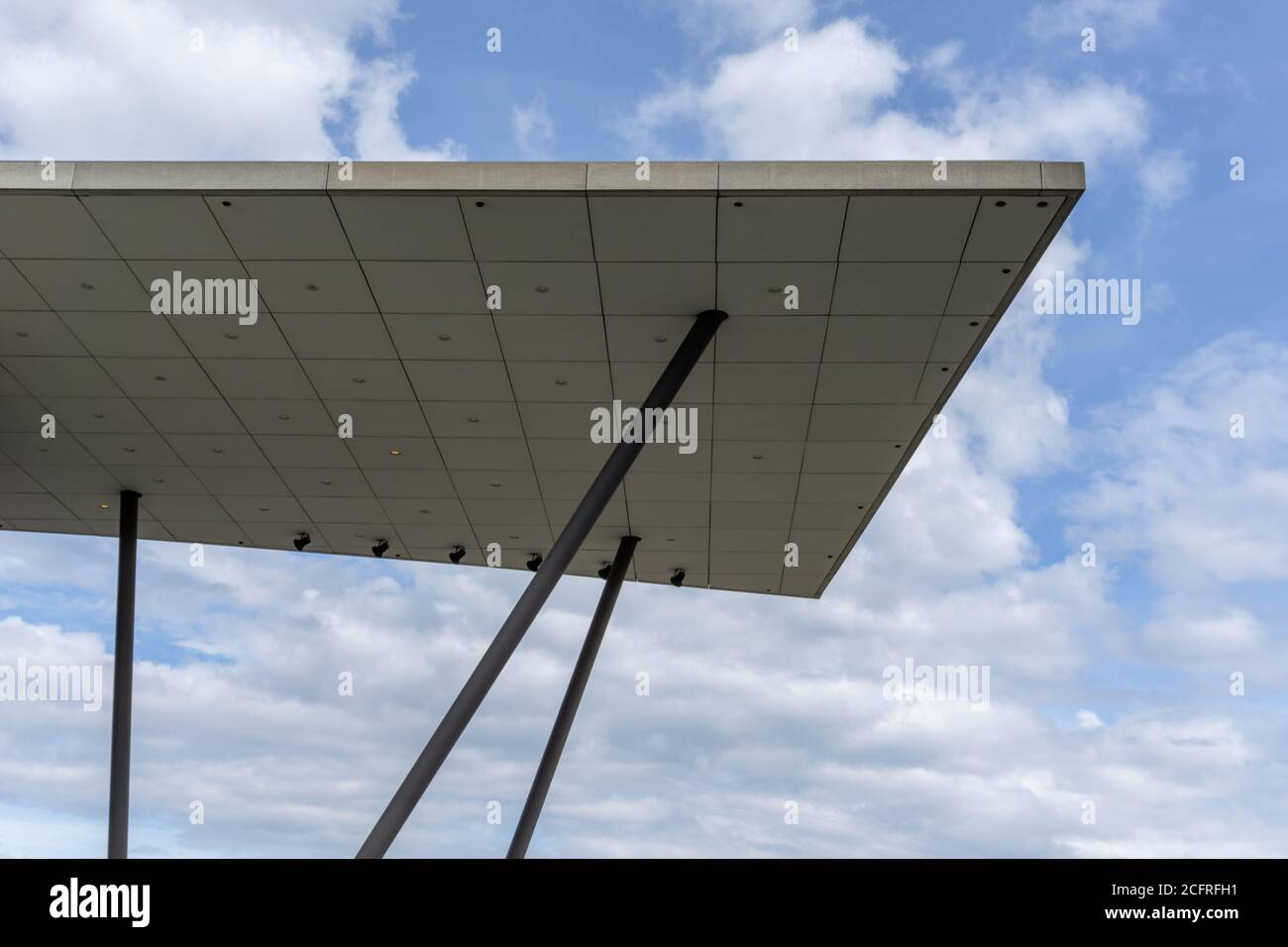 Un tetto in cemento architettonico moderno su tralicci di acciaio con blu e cielo nuvoloso dietro Foto Stock