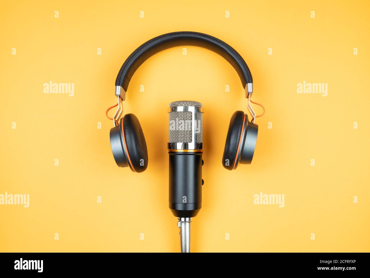 concetto di podcasting, direttamente sopra la vista delle cuffie e microfono di registrazione su sfondo arancione Foto Stock