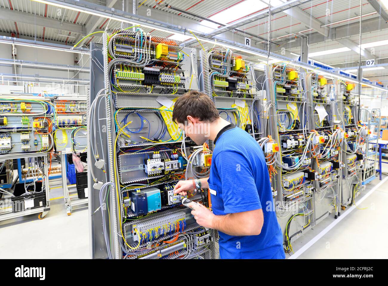 L'uomo assembla i componenti elettronici su una macchina in una fabbrica di ingegneria meccanica Foto Stock