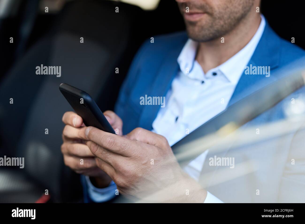 Uomo seduto in macchina e testando sul suo cellulare Foto Stock