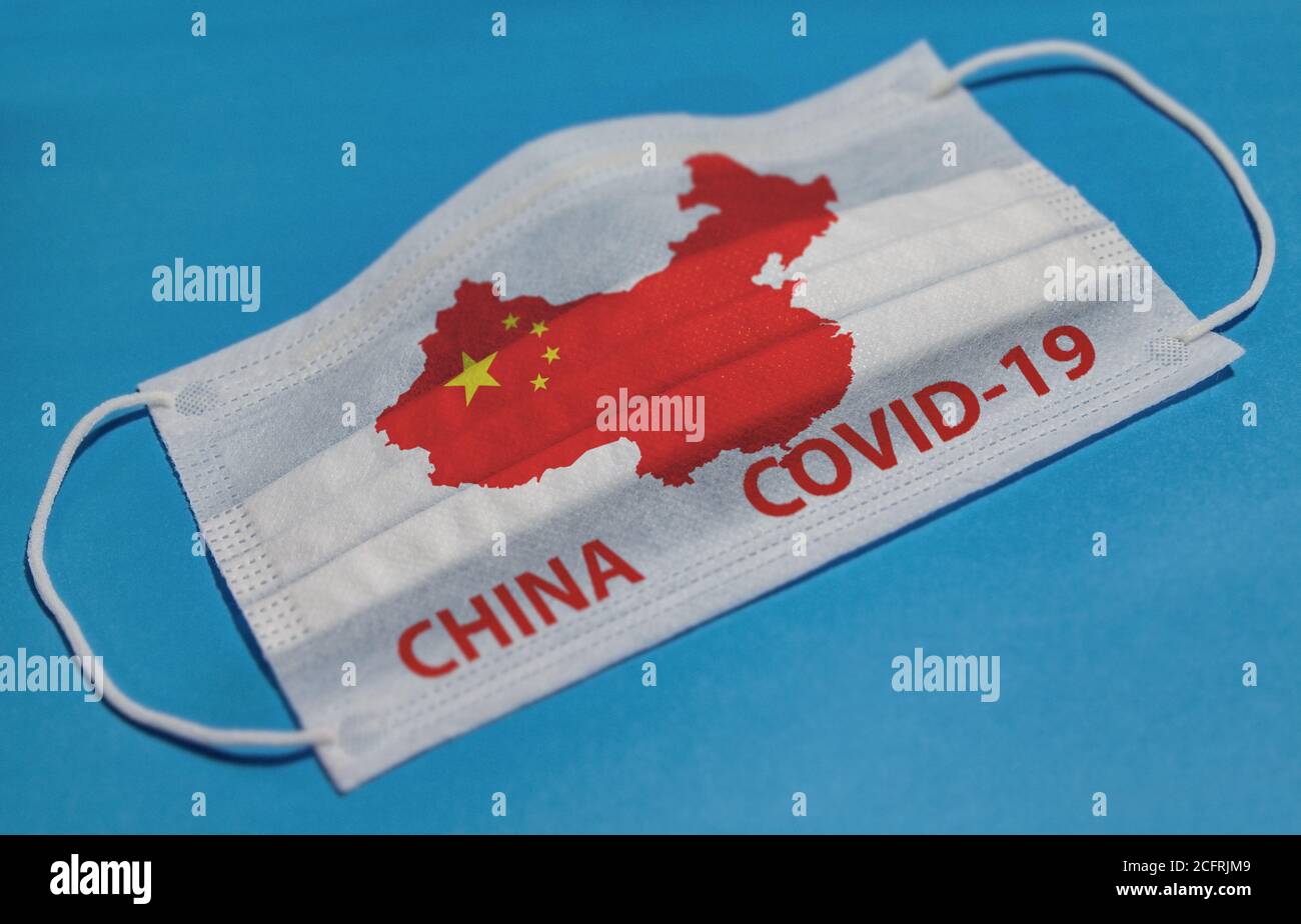 Maschera medica con testo COVID-19 e mappa della Cina su sfondo blu. Concetto di quarantena del coronavirus. Foto Stock