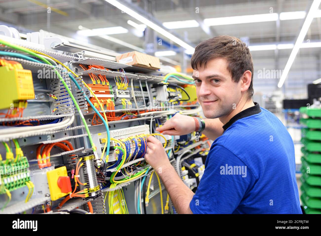 un operatore giovane assembla la macchina in un moderno stabilimento high tech - produzione armadi elettrici per impianti industriali Foto Stock