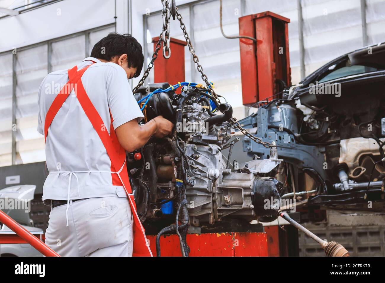 meccanico che assembla un blocco motore di una vettura in servizio in garage in camera Foto Stock